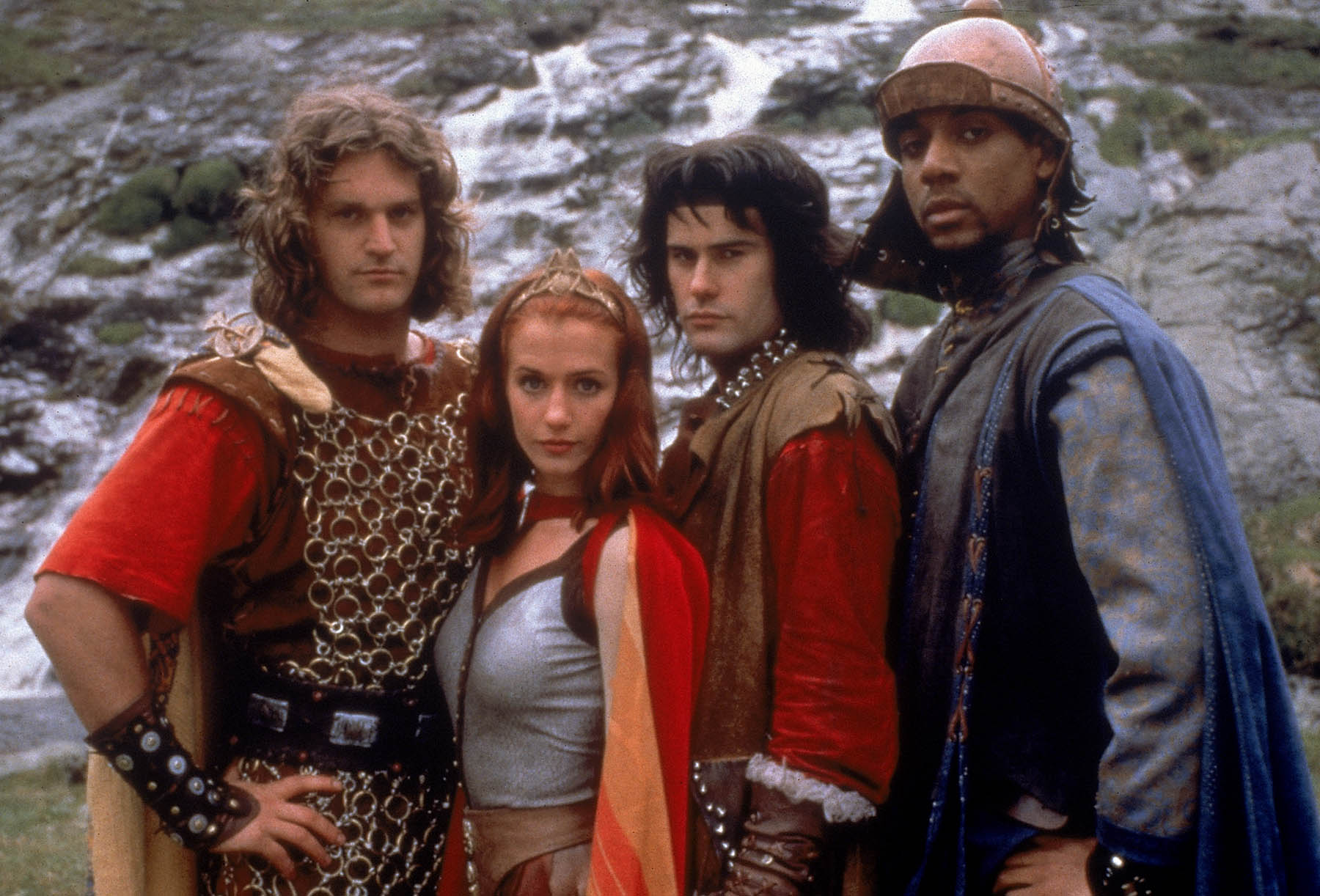 Group shot of the four Mystic Knights standing in front of a mountain and waterfall in the background.