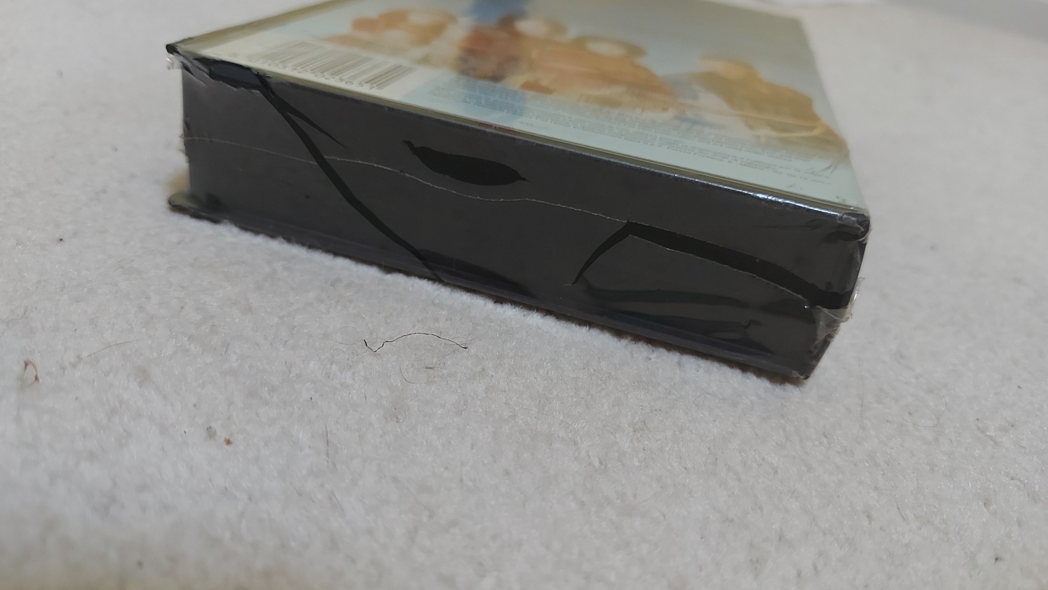Picture of the bottom edge of clamsell VHS tape #2 from the Italian home release. The tape is still sealed in its original plastic, which has split due to its age and brittleness.
